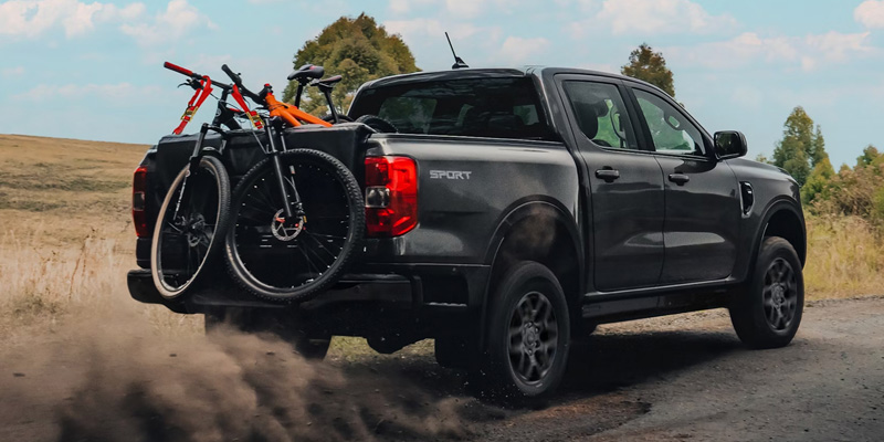 Ford Ranger Sport driving down a dirt path with mountain bikes loaded over the tailgate.